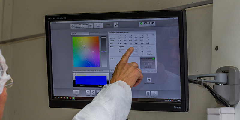 Press operator reviewing a quality control software screen to ensure accurate color consistency in print production